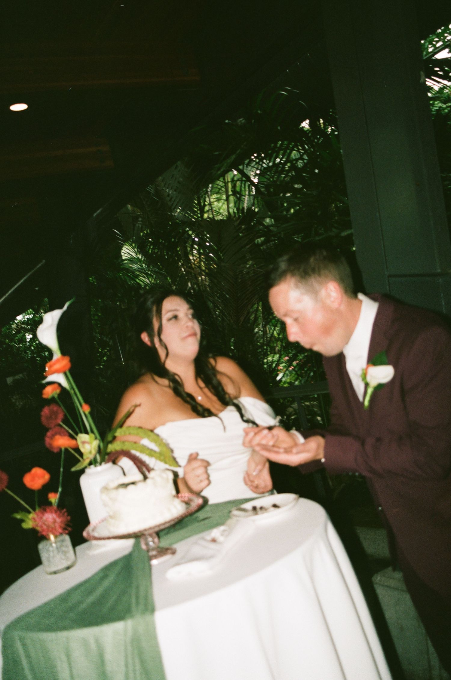 A bride and groom cutting their white wedding cake at an indoor reception venue.