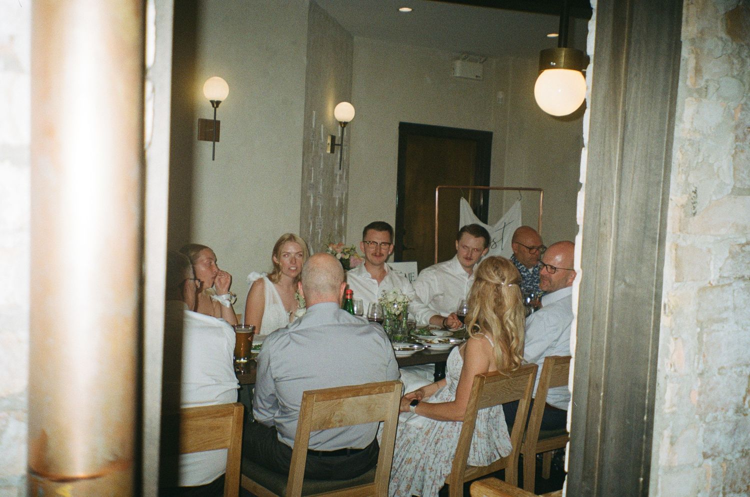 People gathered around a table for dinner in a restaurant with warm lighting and white decor.
