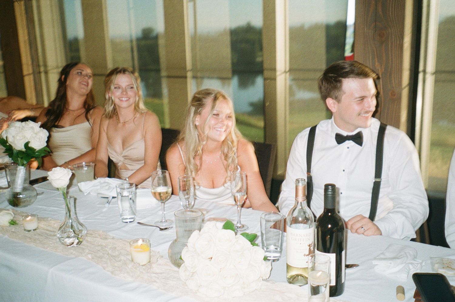 Guests enjoying themselves at an elegant wedding reception with formal table settings and wine bottles.