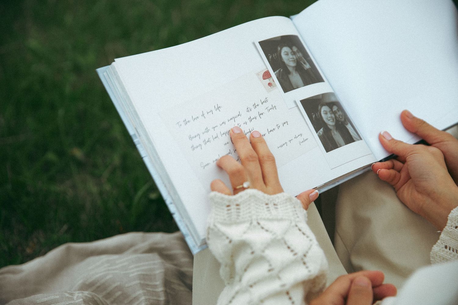 Hands turning pages of a photo album with black and white photographs.
