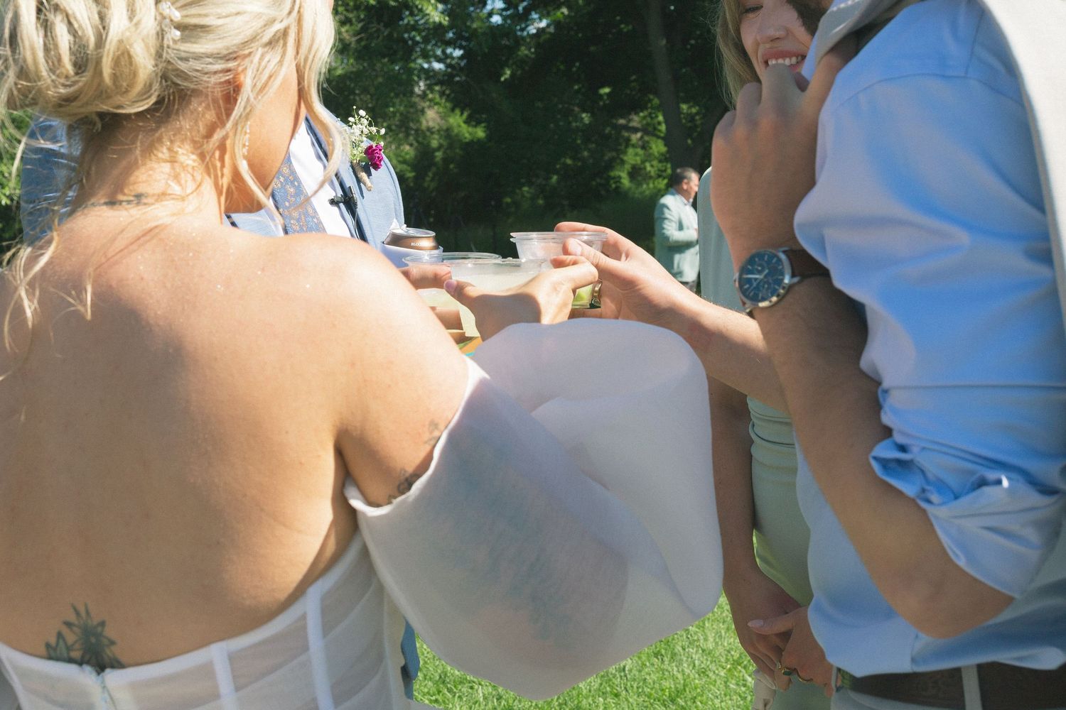 Wedding party members gather outdoors for casual moments during the celebration.