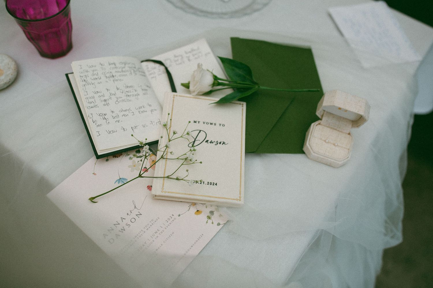 A vintage paper guestbook with elegant script writing lies on a white tablecloth with a green napkin and pen.
