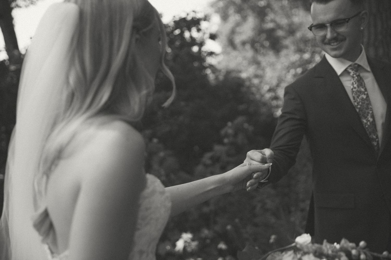 Outdoor wedding ceremony moment captured in black and white as couple bumps fists.