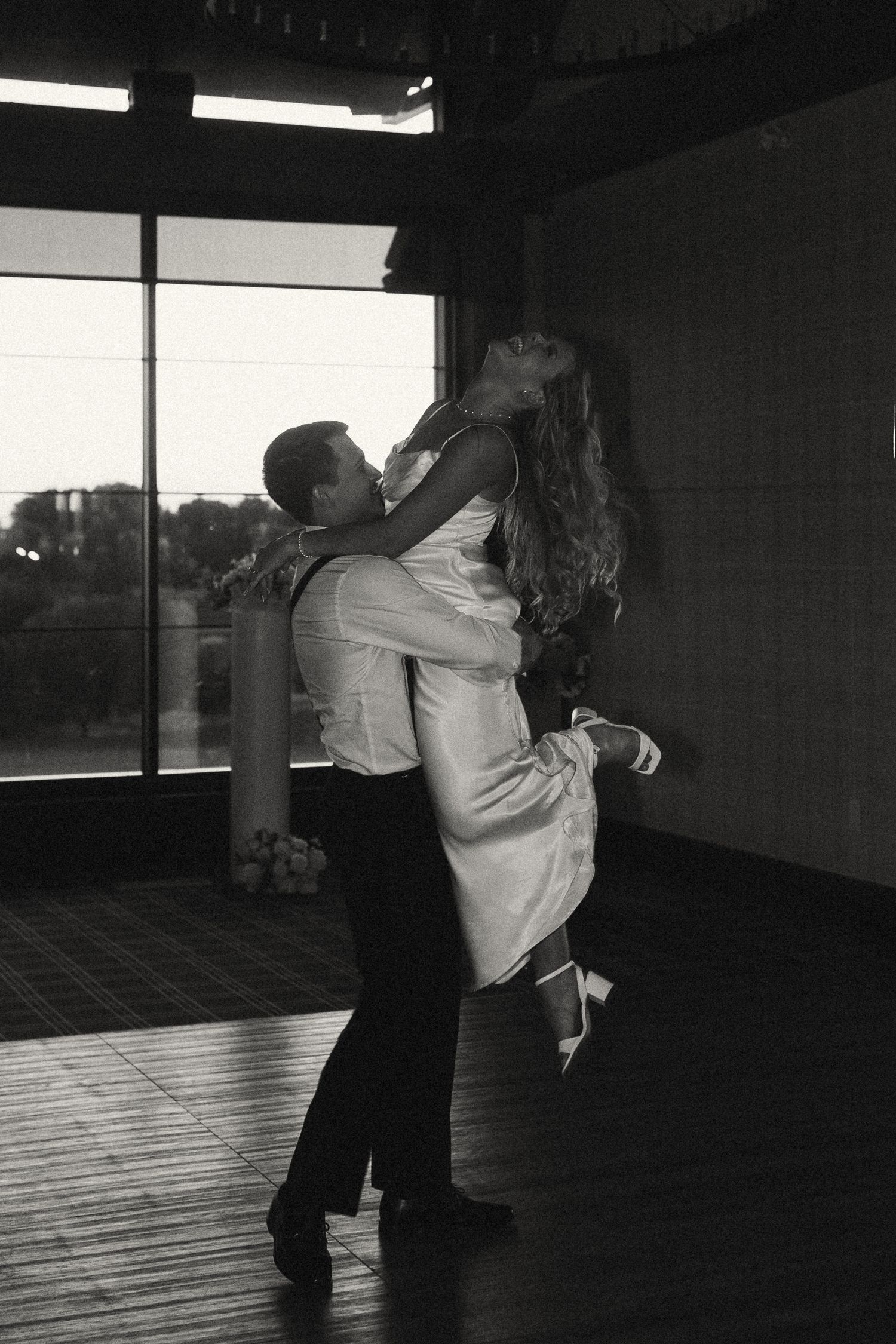 A couple shares an intimate dance moment in black and white photography.