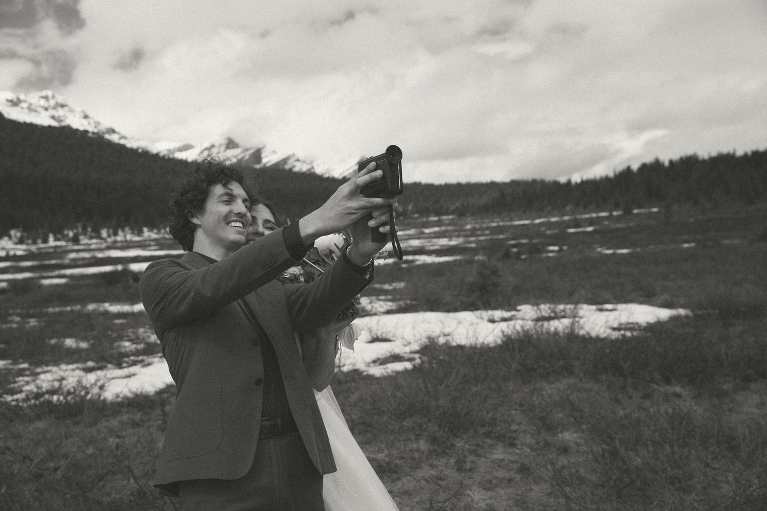 Vintage black and white photograph of someone aiming a rifle across a snowy winter landscape.