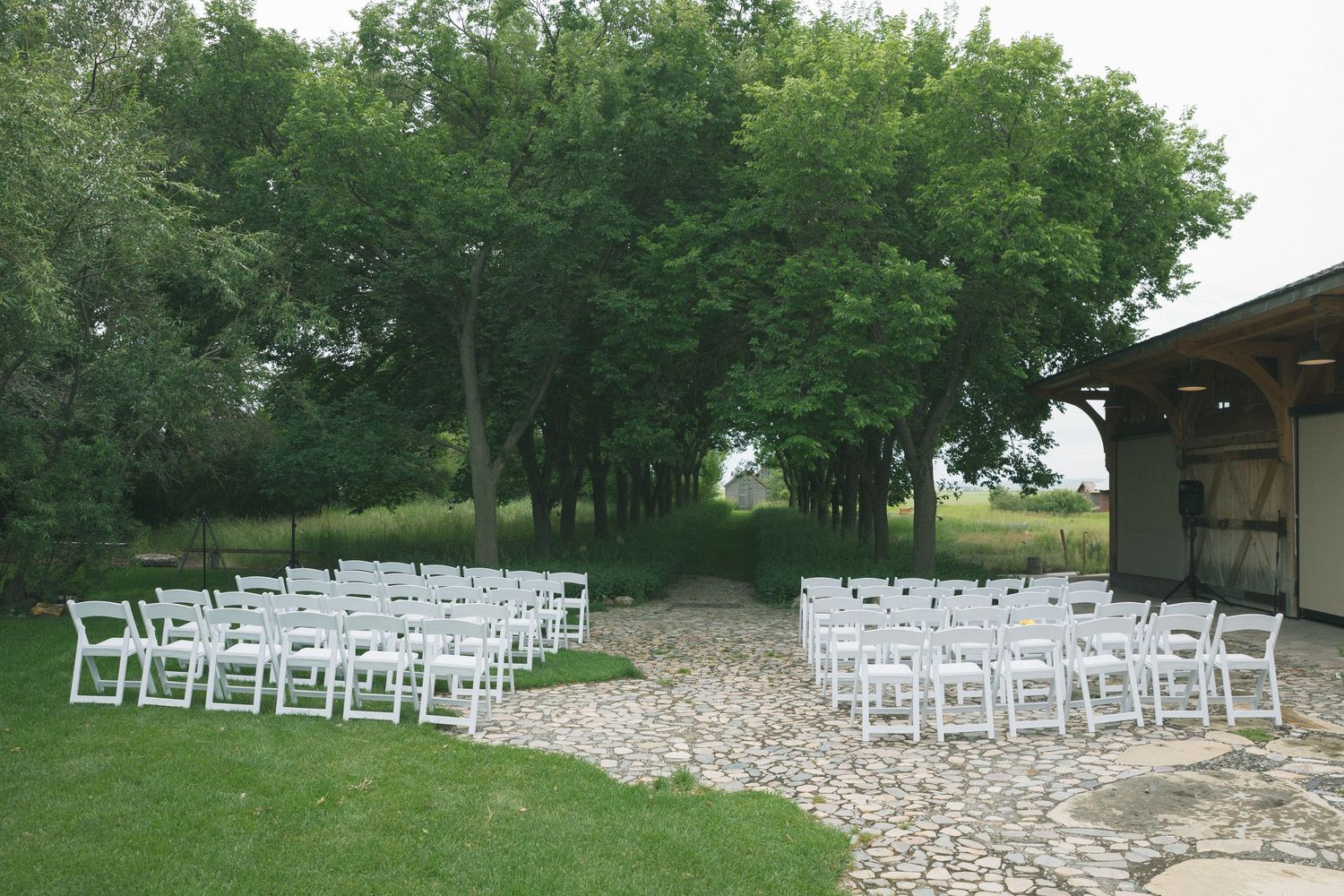 White chairs arranged in rows on a stone patio for an outdoor wedding ceremony.