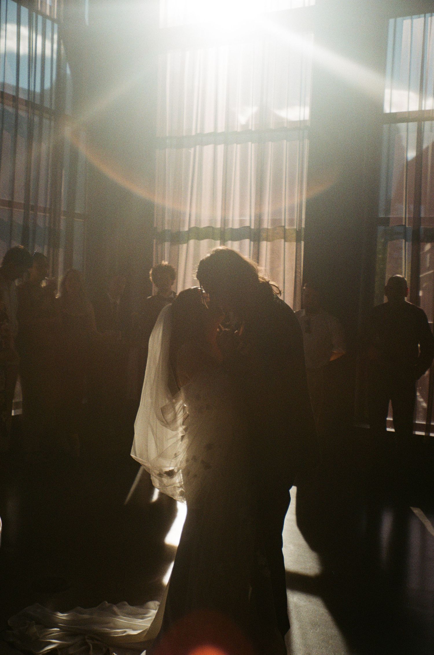 Silhouetted figures dance in dramatic backlighting through tall windows.