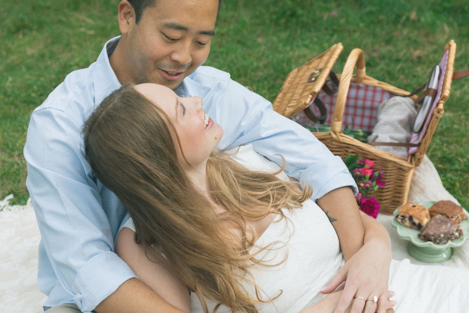 A romantic picnic scene with a wicker basket on green grass.