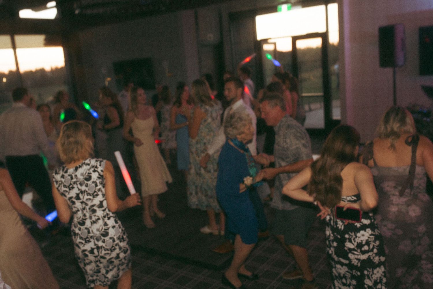 Wedding guests dance with light-up props on a dimly lit dance floor.