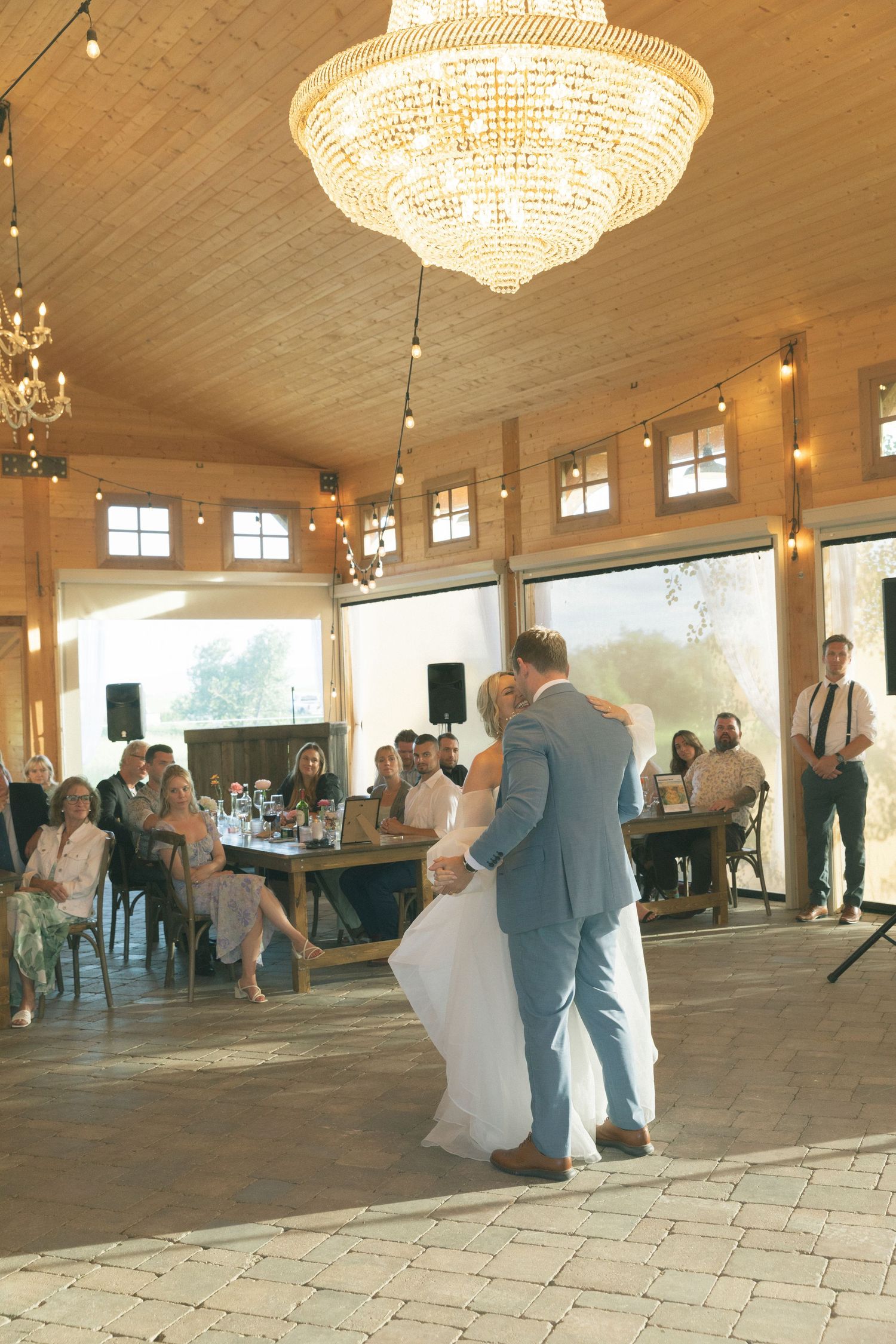 Wedding reception in progress inside elegant ballroom with crystal chandeliers.