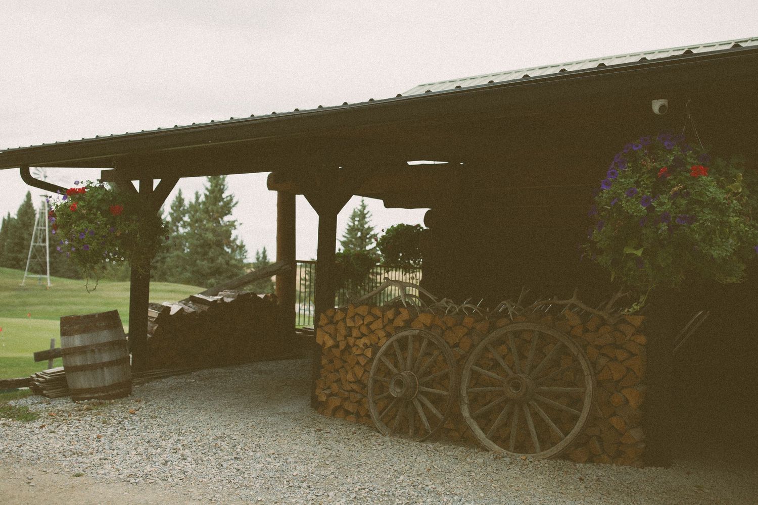 Rustic covered area with vintage wagon wheels and floral decorations.