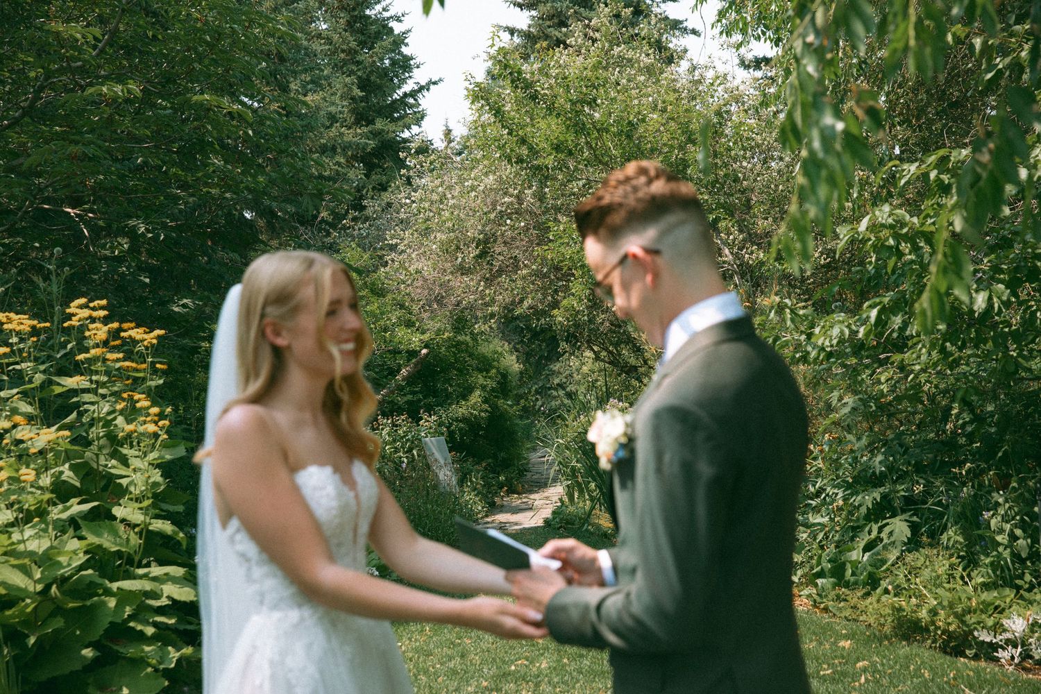 A couple exchanges wedding rings during an outdoor garden first look