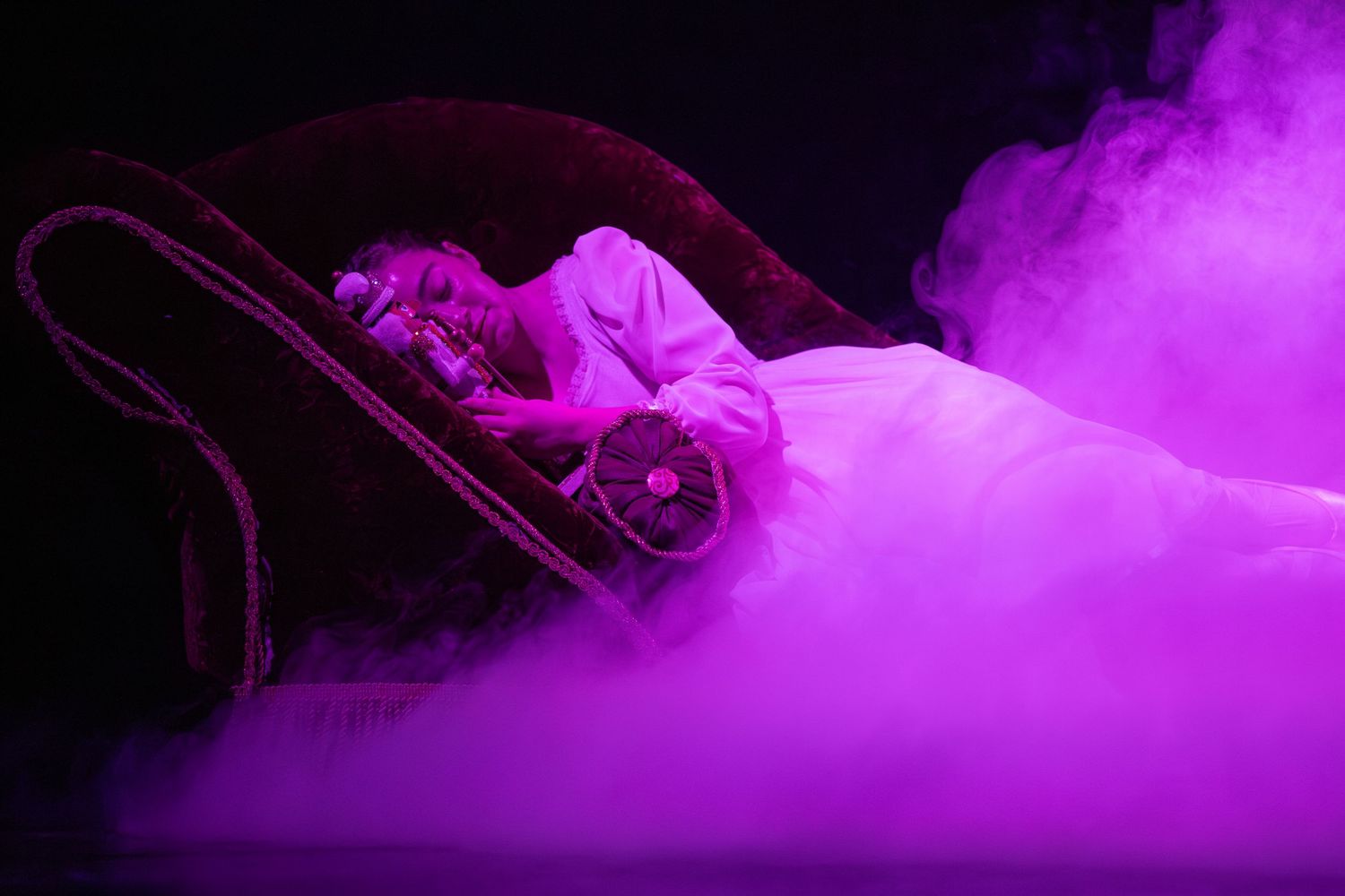 Dramatic scene with fog effects and purple lighting on theatrical stage.