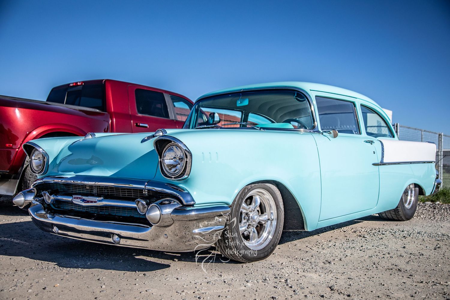 A classic mint green 1957 Chevrolet Bel Air lowrider with chrome trim and custom wheels parked under blue sky.