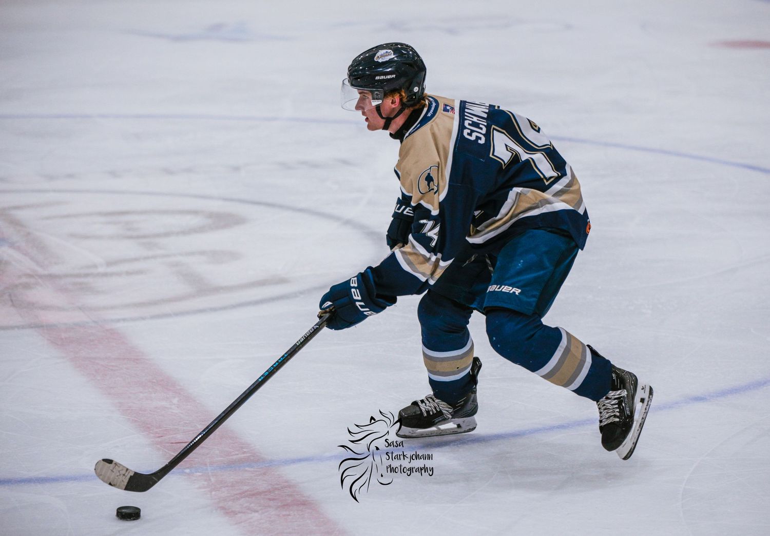 Hockey player in navy and tan uniform skillfully controls puck while skating.