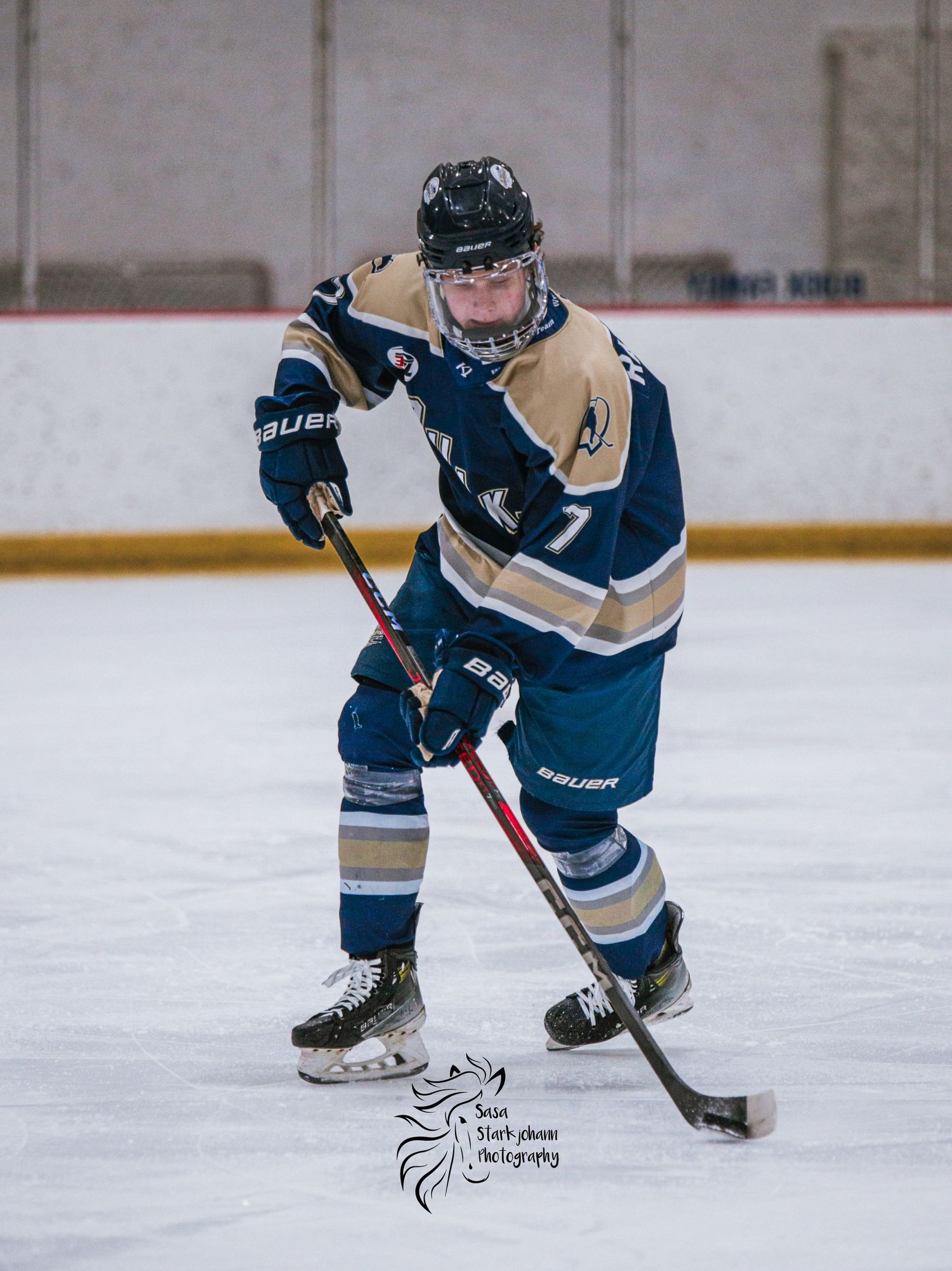 Hockey player in blue and tan uniform controls puck during game.