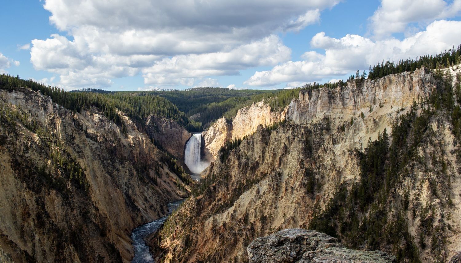 Dramatic view of Lower Falls waterfall in Yellowstone's Grand Canyon with steep rock walls.