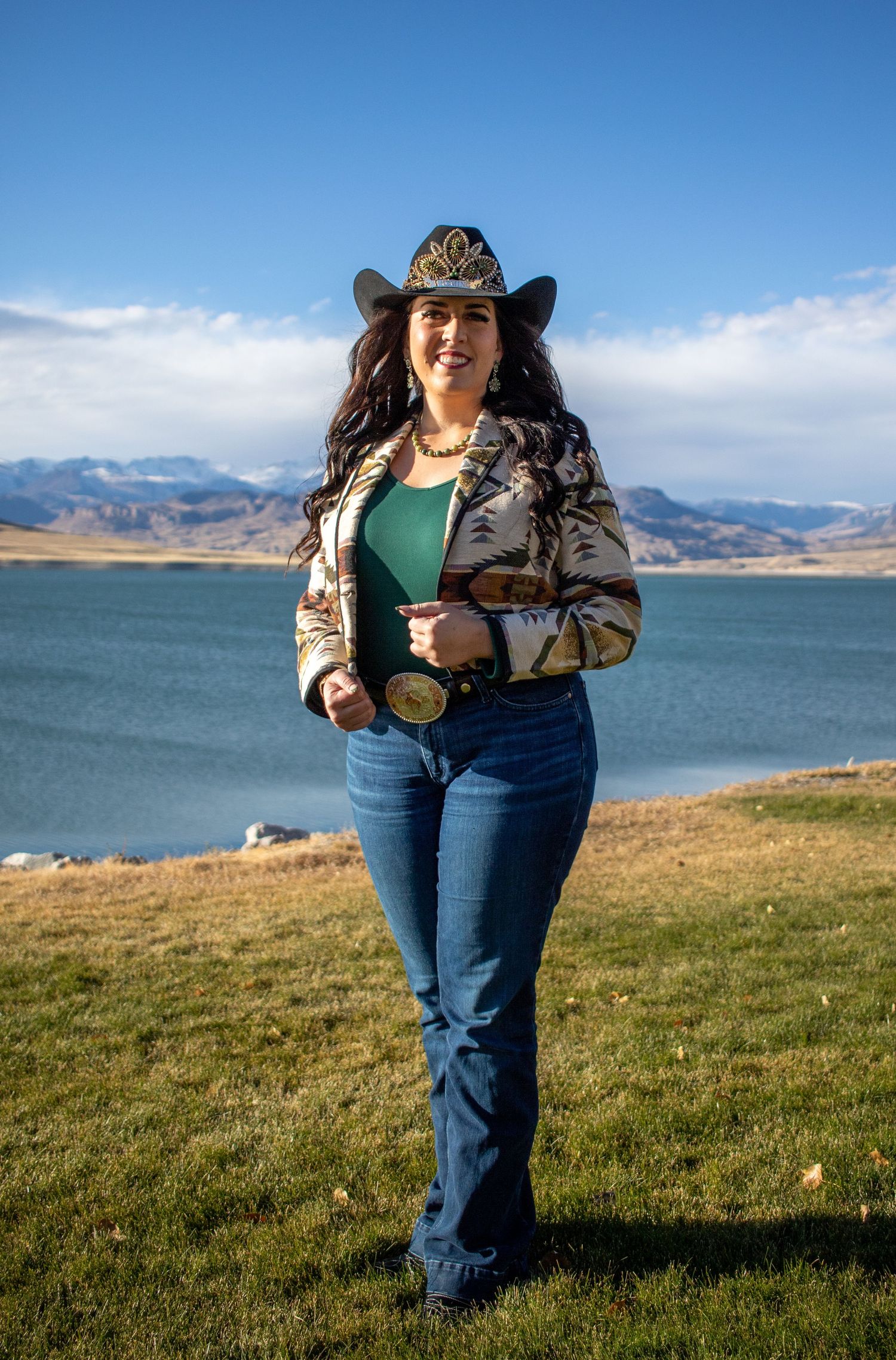 A western-styled portrait by a lake with mountains in the background.