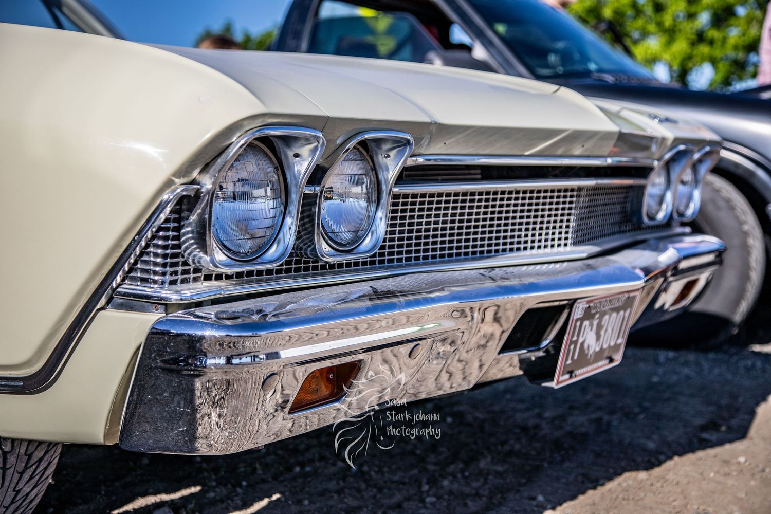 Close-up view of vintage Chevrolet car front end showing chrome grille, dual headlights and polished chrome bumper.