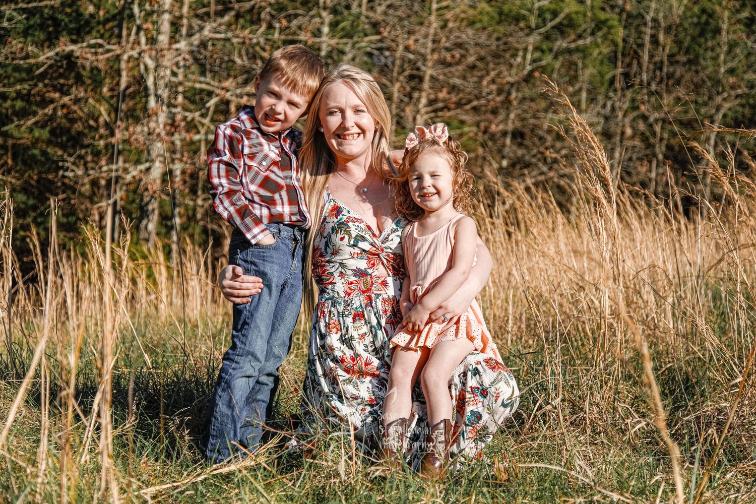 Loving family poses together in a golden field wearing coordinating outfits for a casual photo.