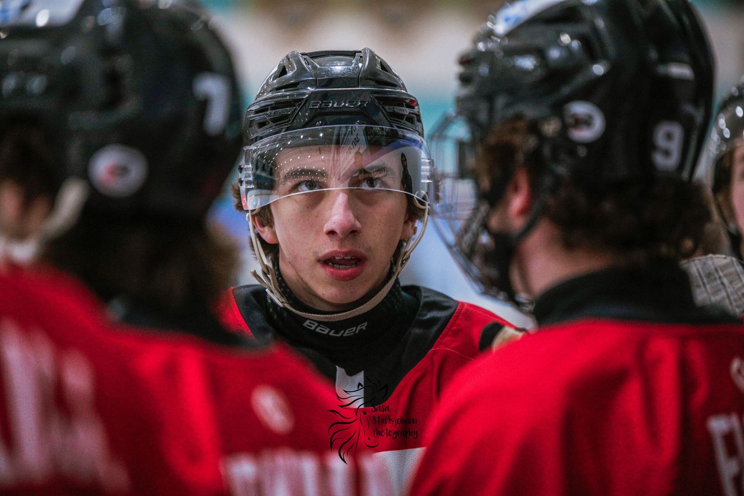 Ice hockey players huddle during game discussion.