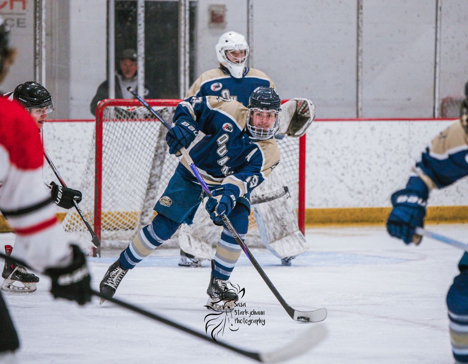 A hockey player in blue jersey maneuvers with the puck during gameplay.