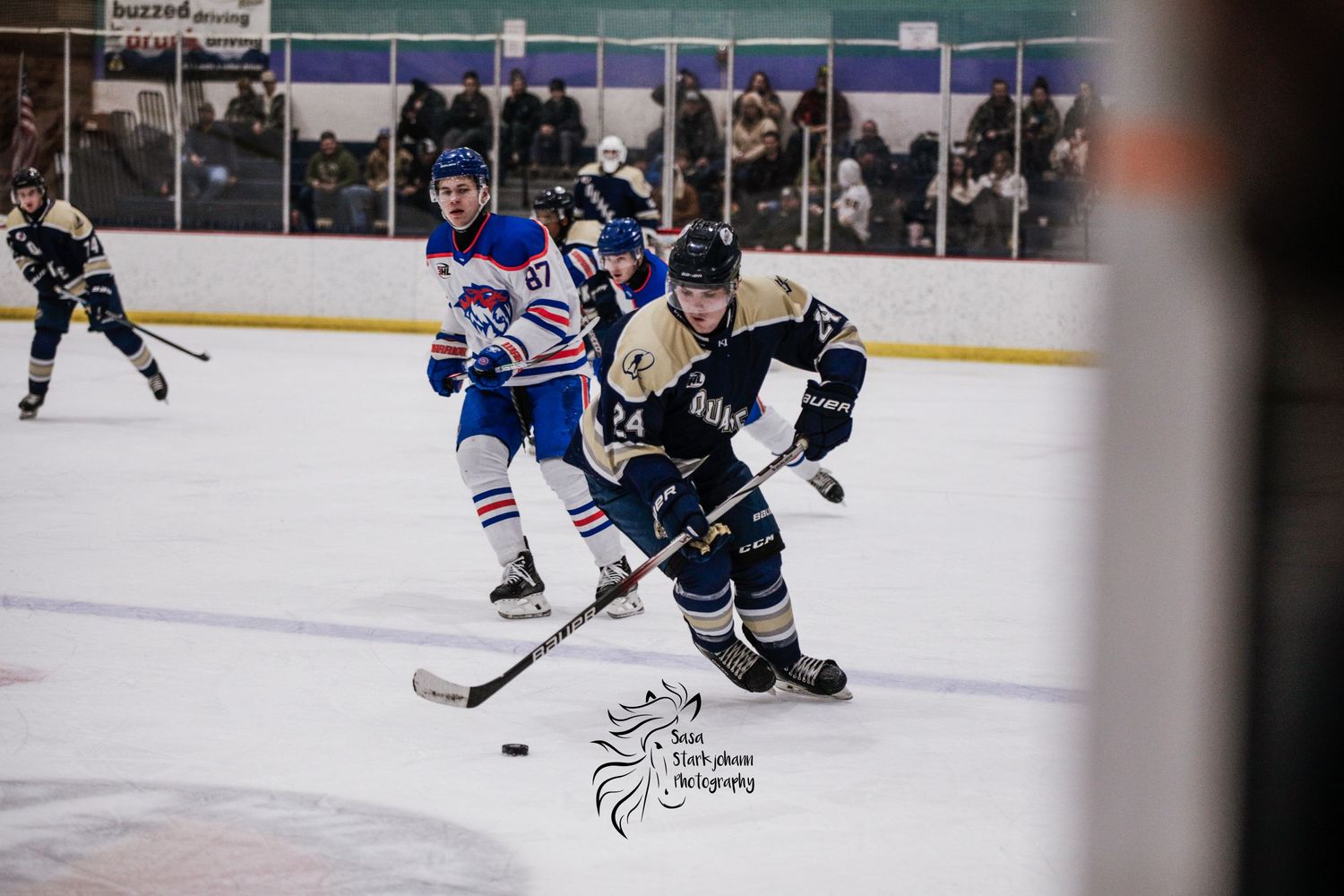 Hockey players from opposing teams compete for puck control during intense game action.