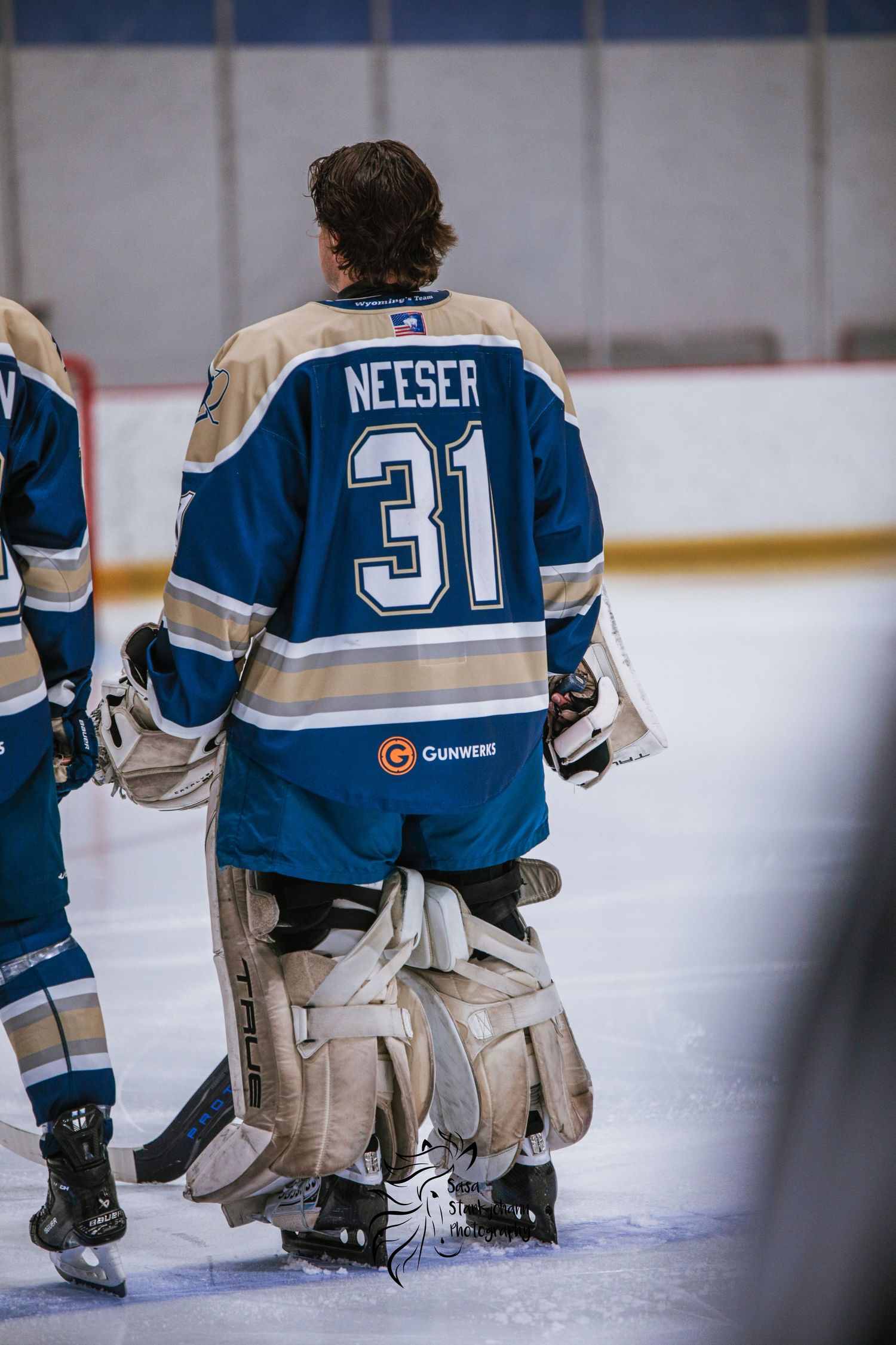Hockey goalie Wieser number 31 shown from behind on ice rink.