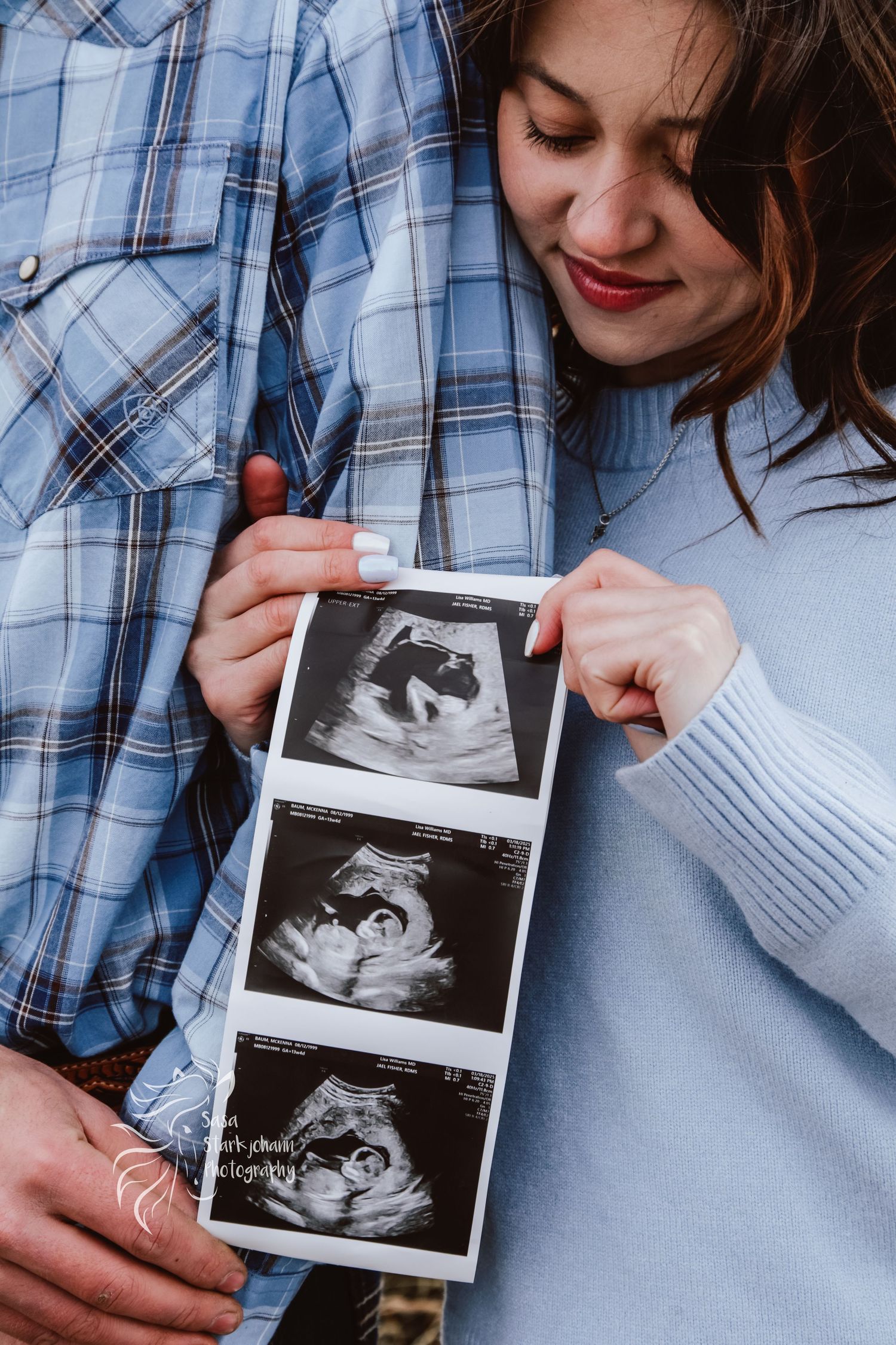 A couple holds ultrasound images while sharing an intimate moment.