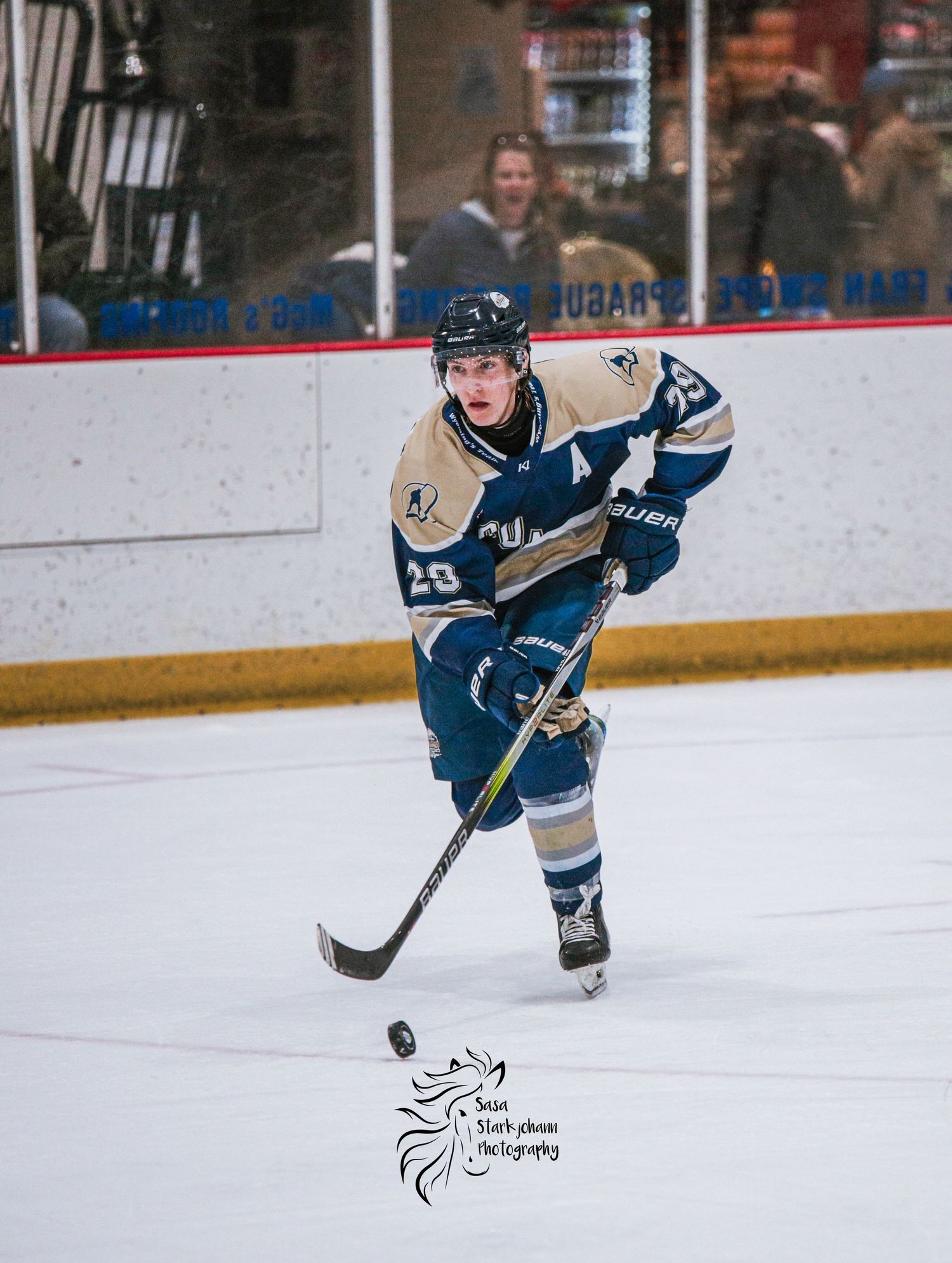 Hockey player in blue jersey controlling puck during competitive game.