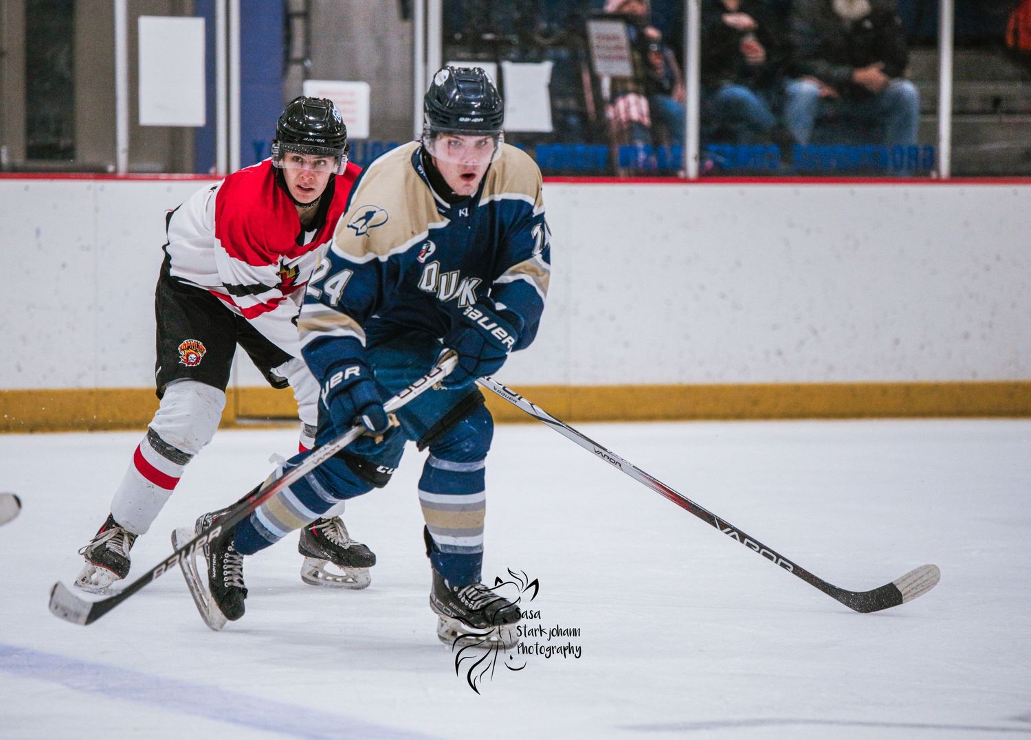 Ice hockey players from opposing teams battling for puck control during intense game action.