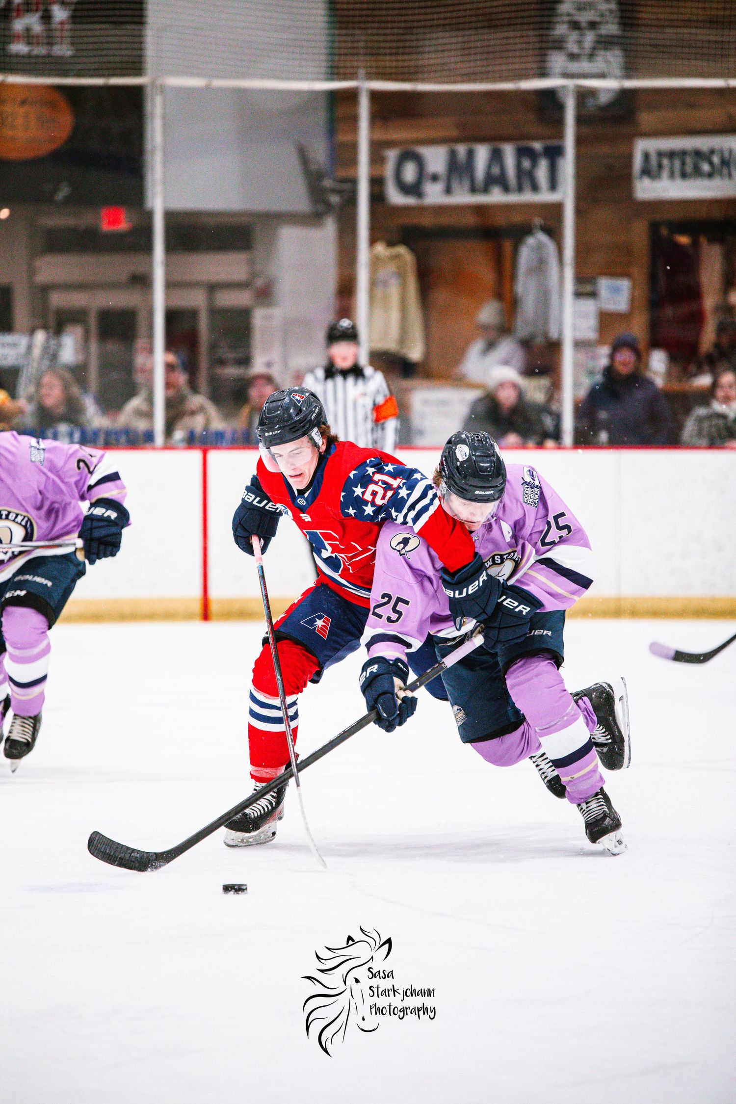 Hockey players in red and purple jerseys battle for puck during competitive match.