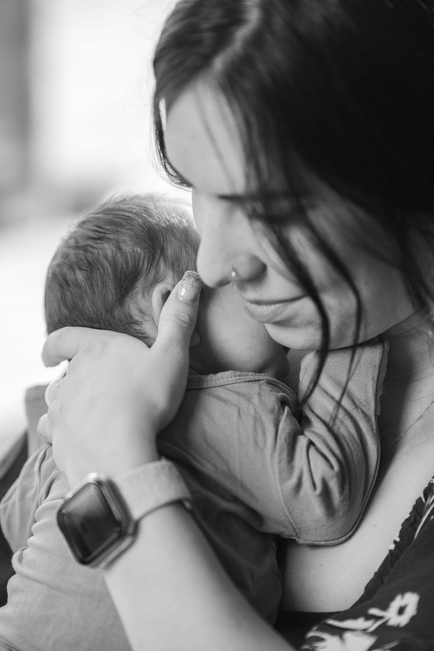 A tender black and white photo series showing intimate moments between a parent and newborn baby.