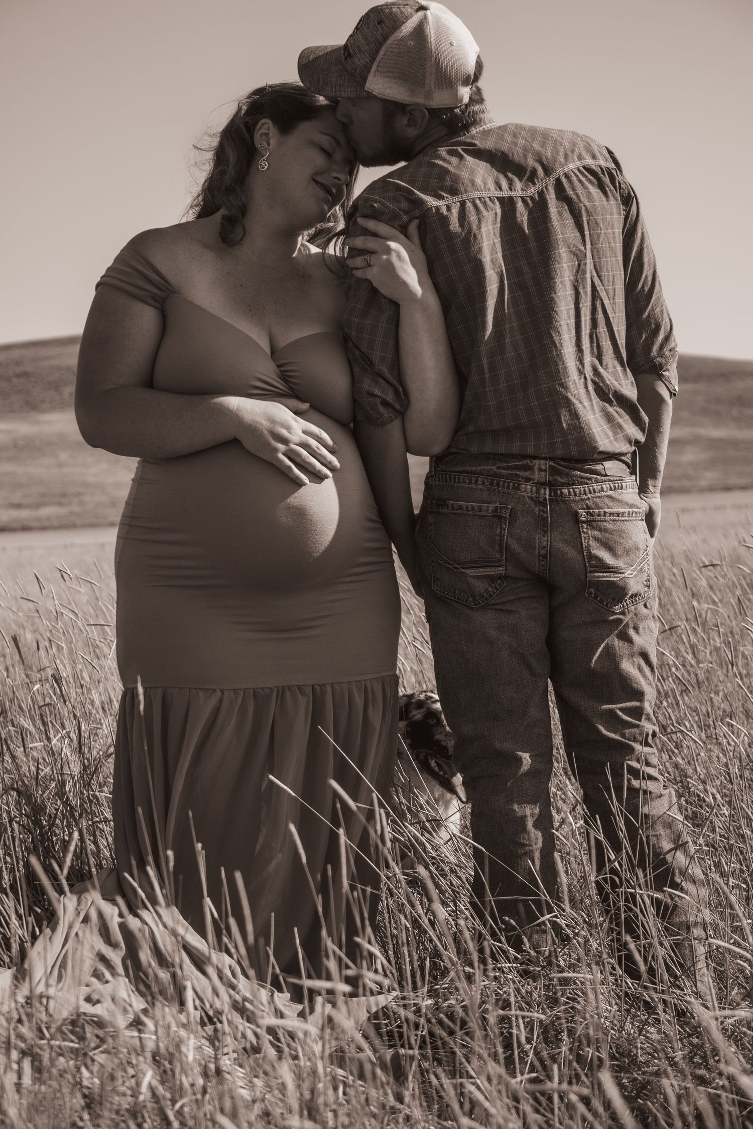 A couple sharing an intimate moment in a field at sunset.