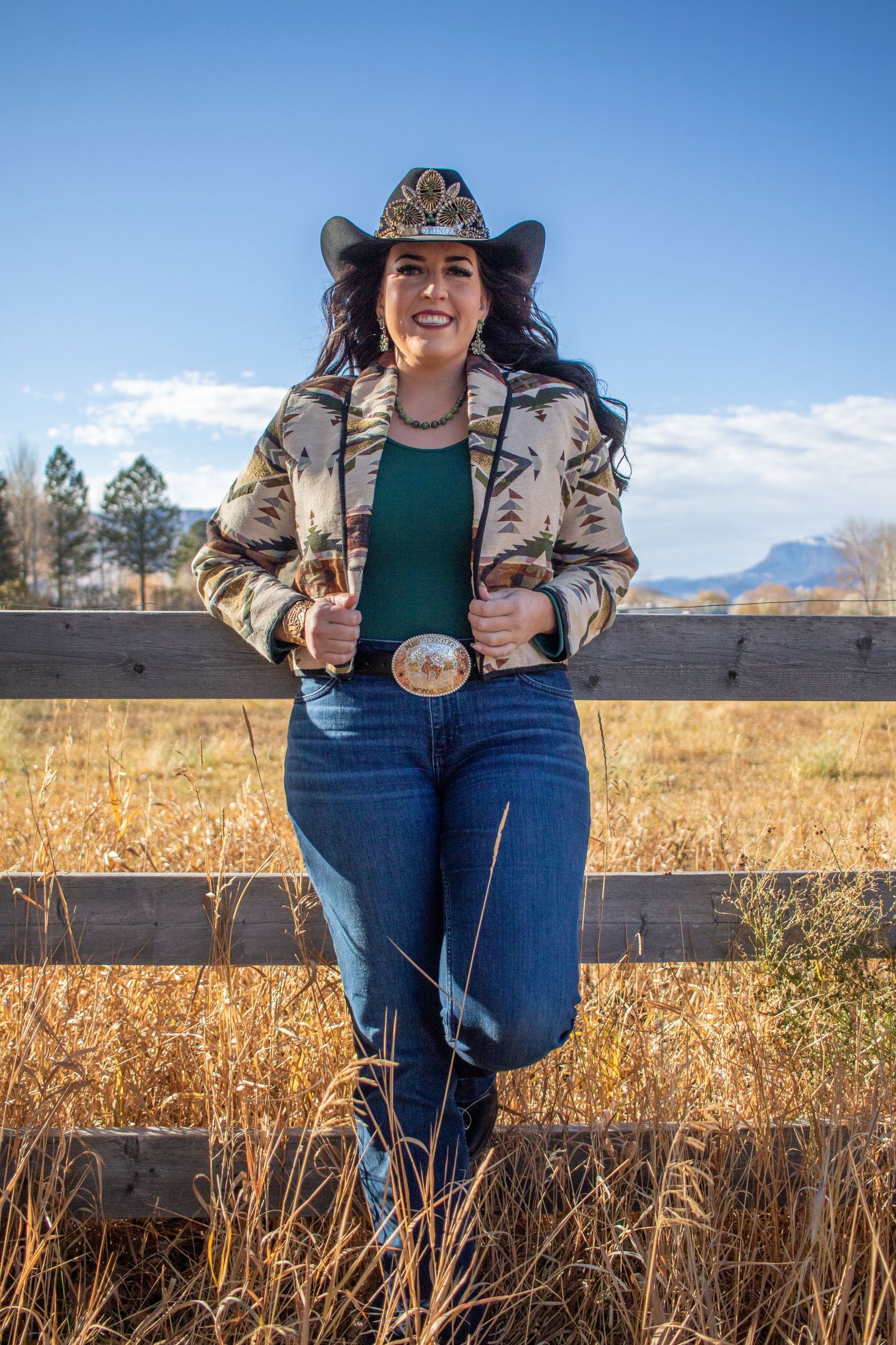 A western-style portrait featuring a cowboy hat and decorative jacket against a mountain backdrop.