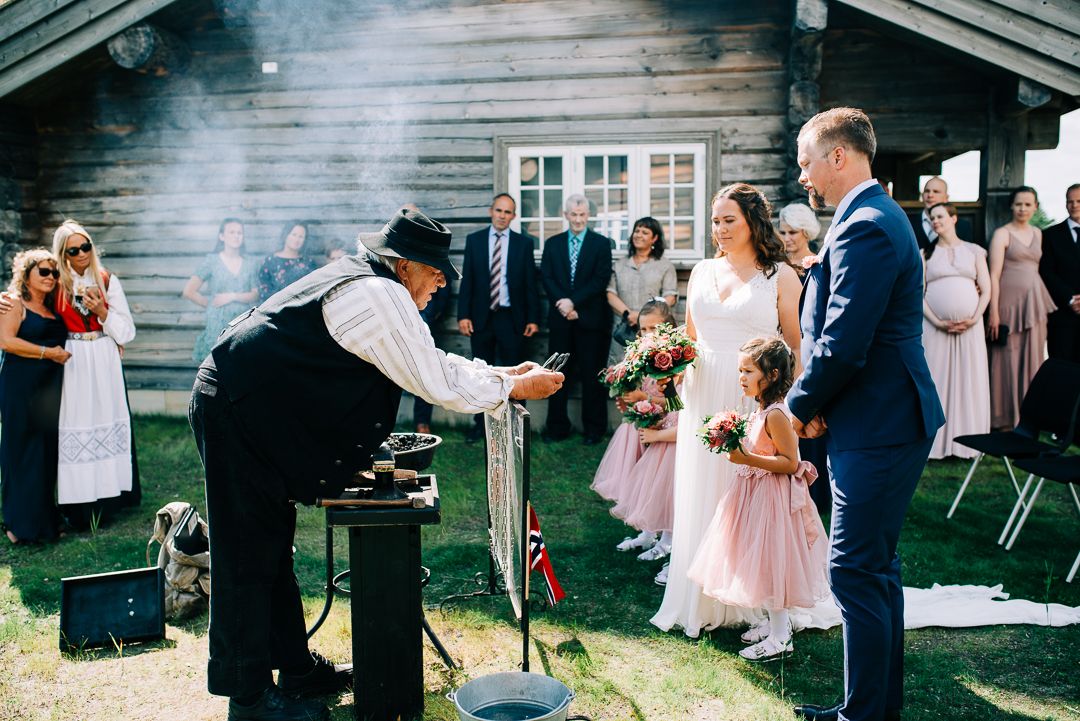 Blacksmith in traditional attire demonstrates metalworking during outdoor wedding celebration.