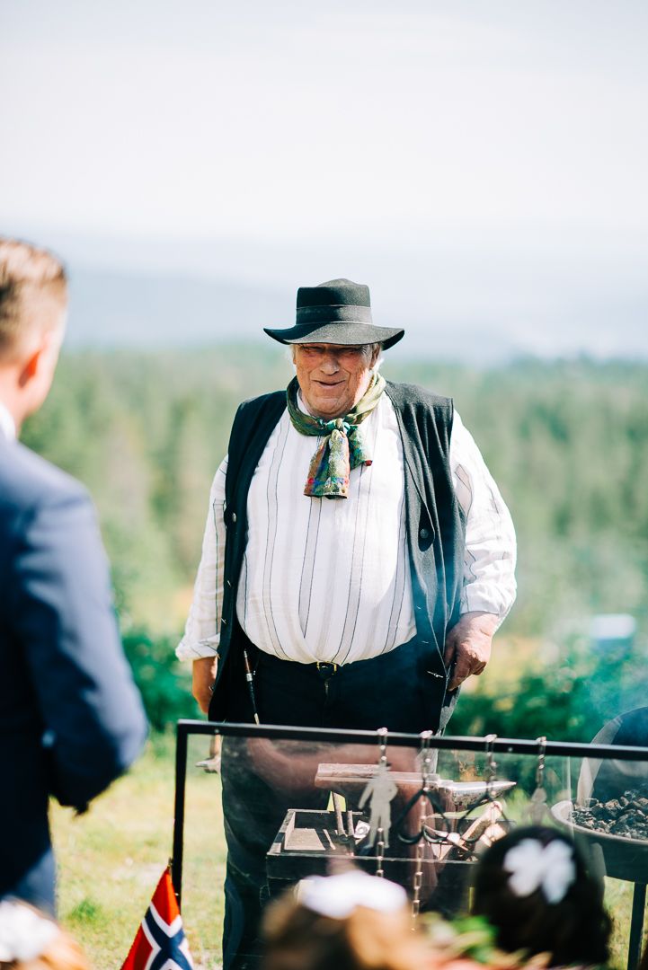 Traditional Norwegian cook in period costume preparing food at outdoor mountain wedding.