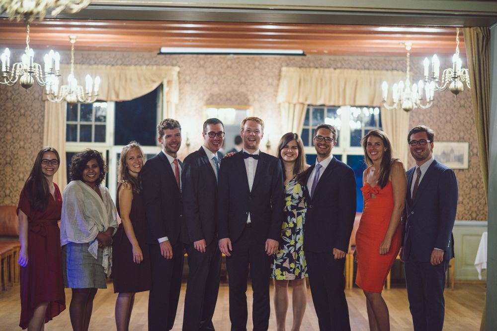 Formal group photo of wedding party members in an elegantly decorated reception hall.