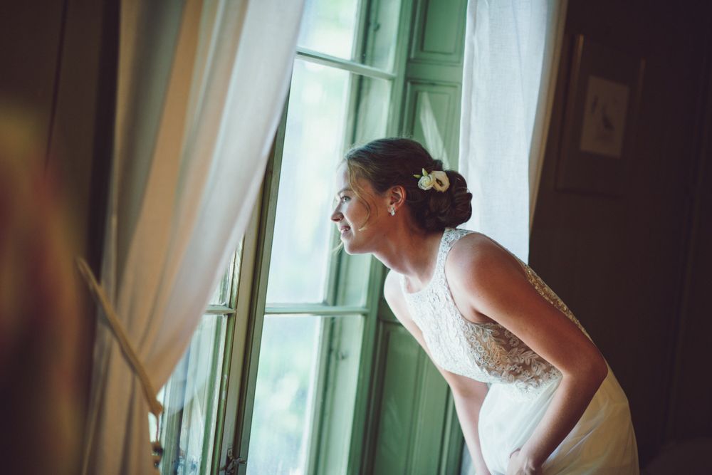Wedding preparation scene at a window with soft natural light streaming in.