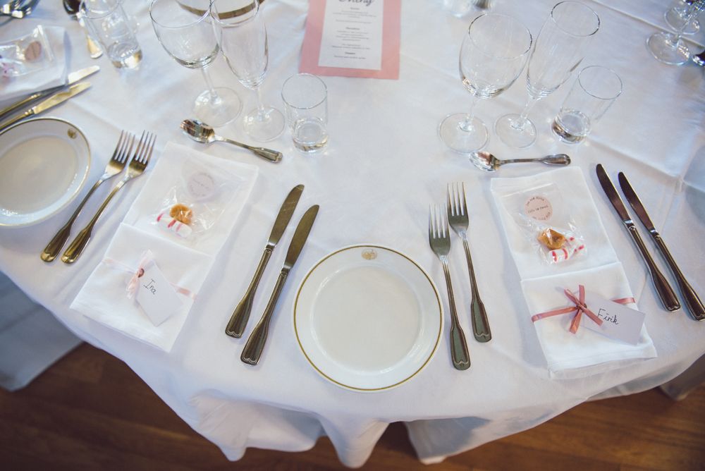 Elegant wedding table setting with white linens and formal place settings.