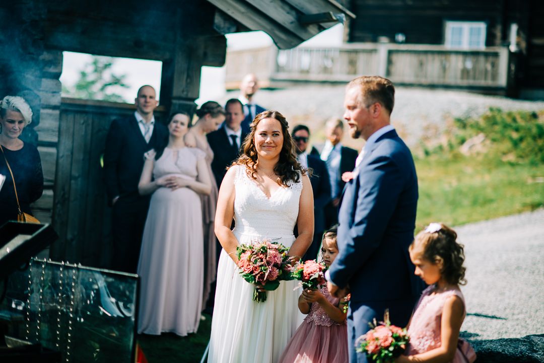 Outdoor wedding ceremony with attendants in pink dresses gathered near vintage train car.