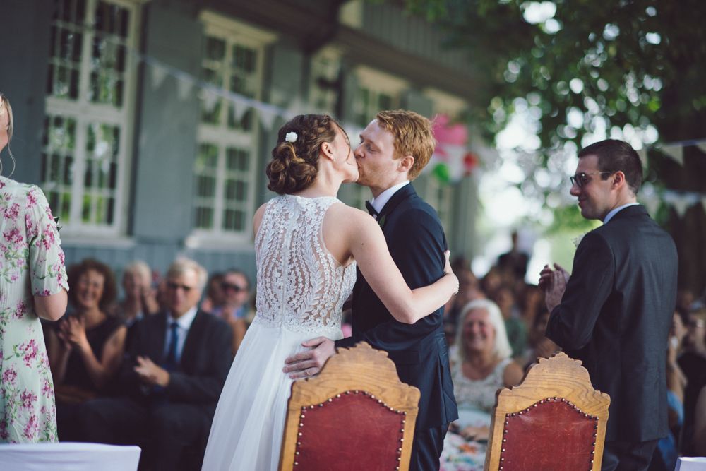 Intimate wedding ceremony moment with decorative red chairs.