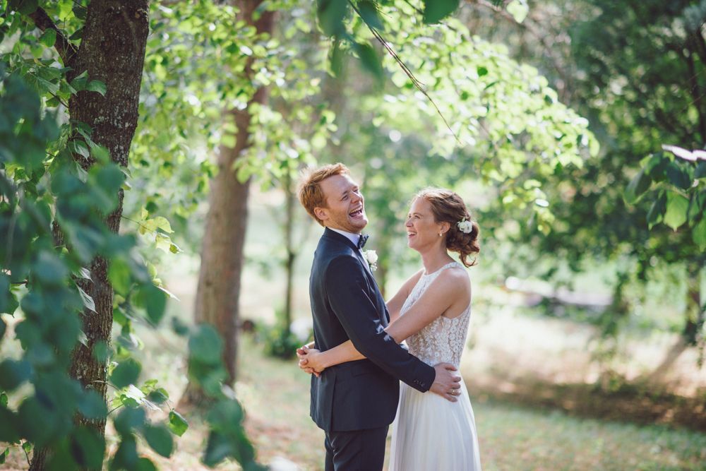 A joyful wedding moment shared between a couple in a sunlit forest setting.