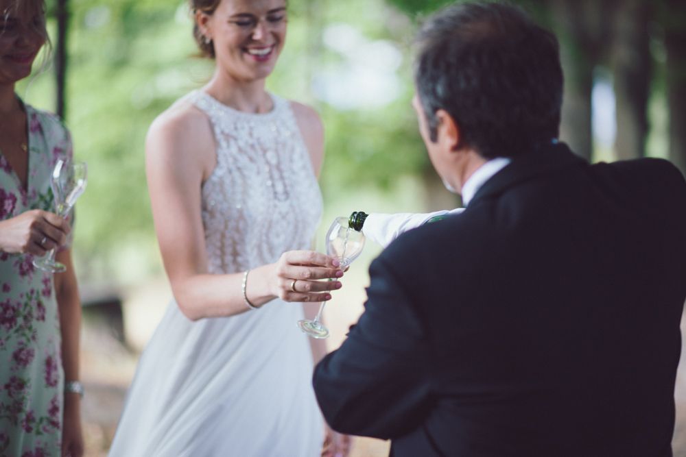 Exchange of rings during outdoor wedding ceremony beneath green trees.