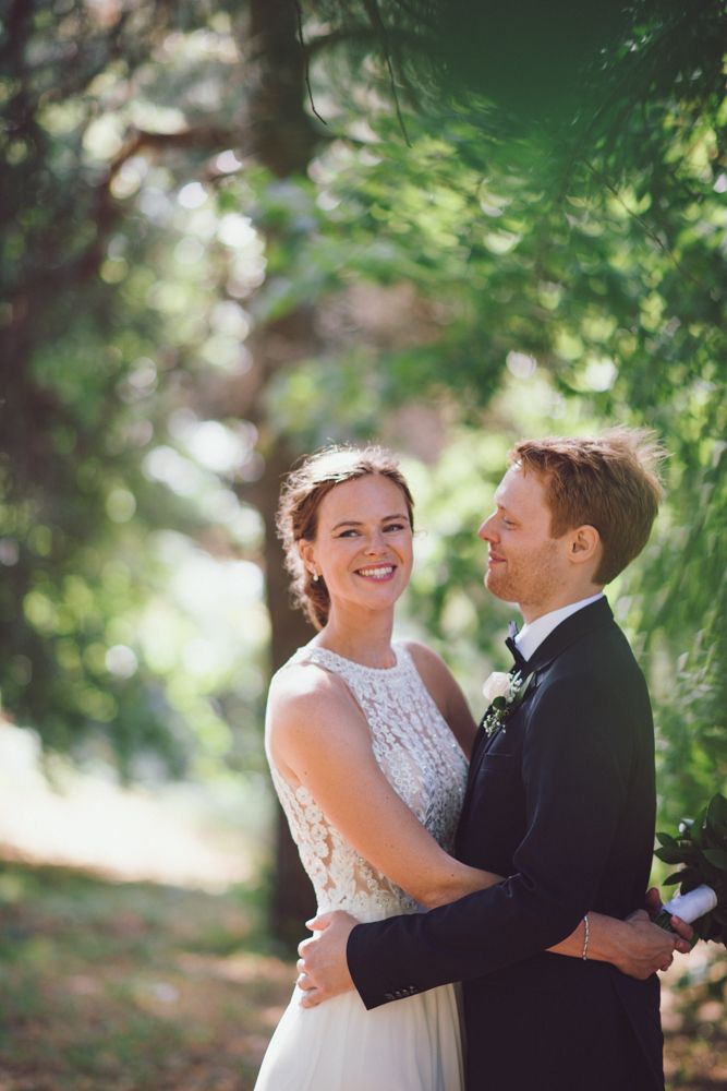 A romantic outdoor wedding portrait surrounded by dreamy bokeh and green foliage.