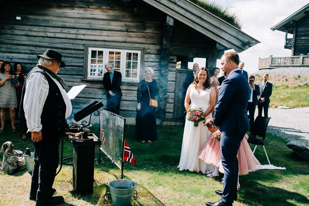 Traditional Norwegian wedding celebration outside rustic wooden cabin with historic costumes.