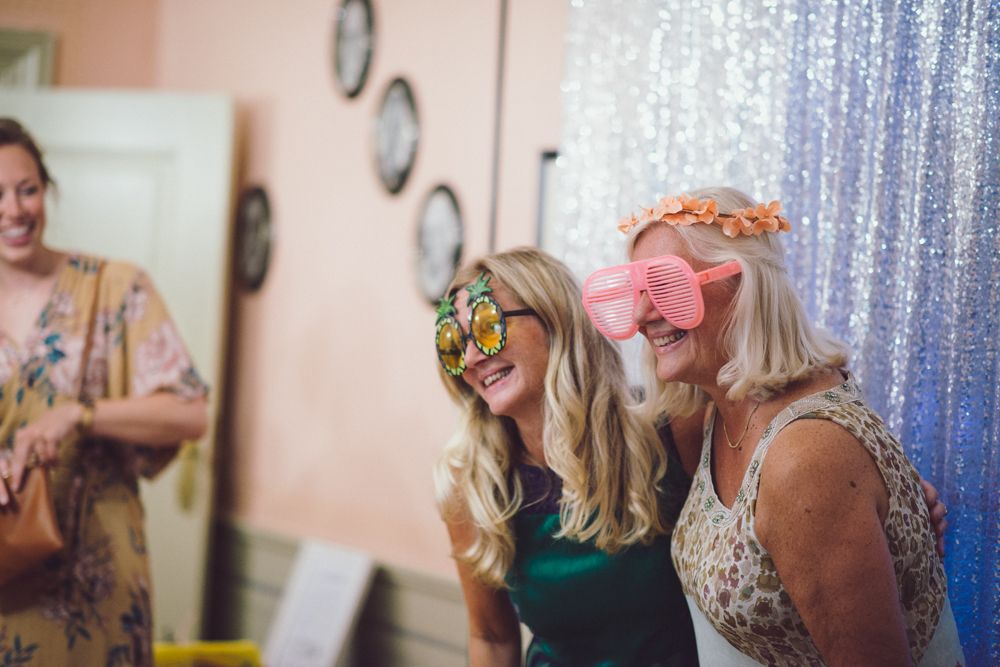 Wedding guests wearing fun masks and flower crowns at a celebratory party.