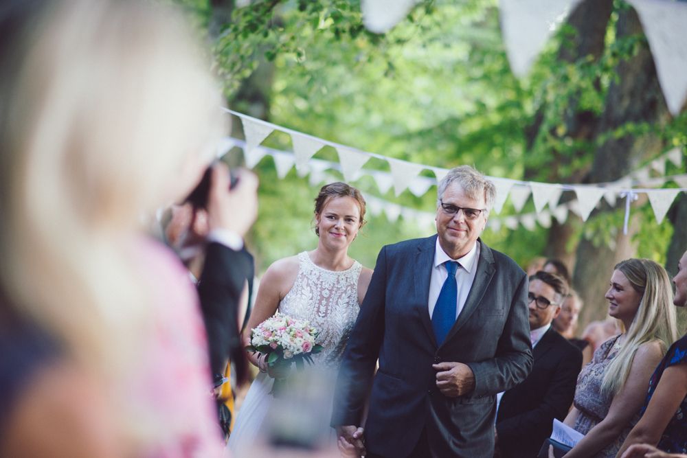 Outdoor wedding processional with white bunting decorations.