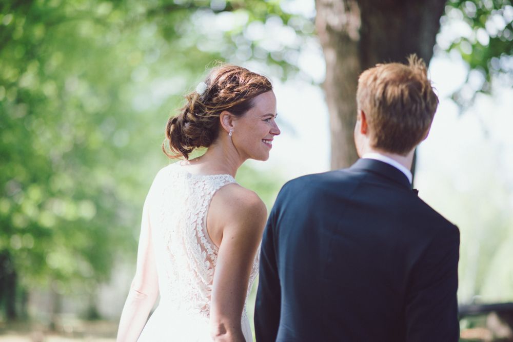 Close up view of lace back detail on wedding dress against greenery.