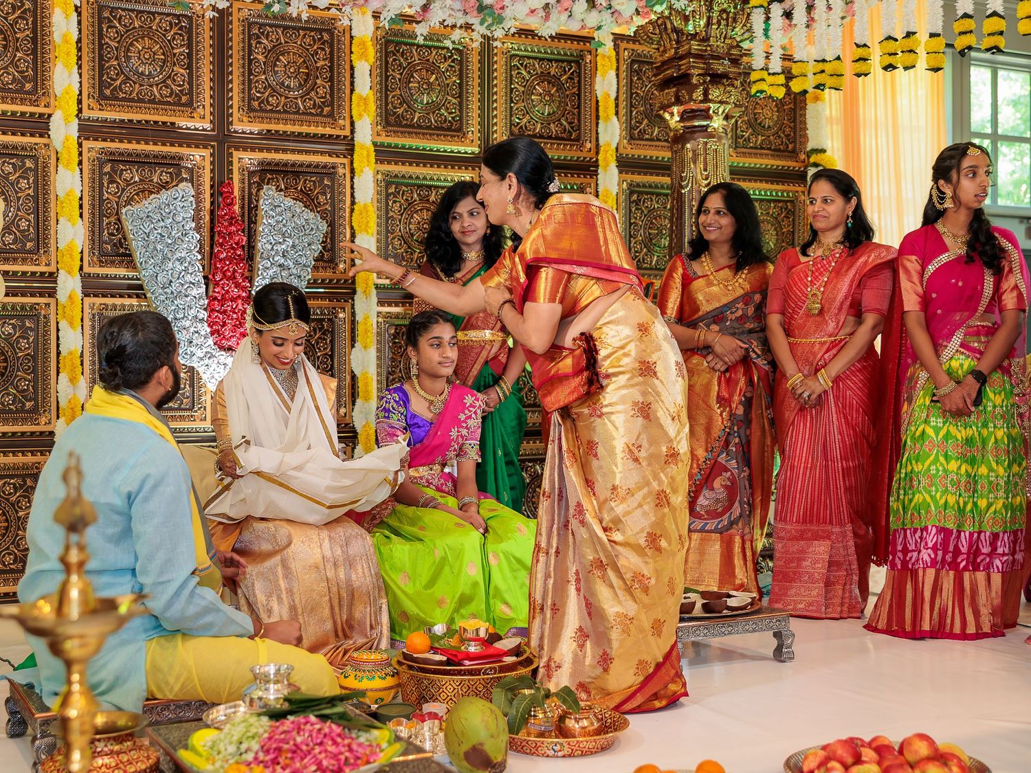 Traditional Indian wedding ceremony with priests performing rituals as guests in colorful saris look on.